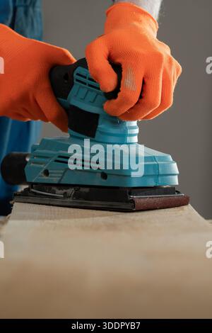 Close-up of man hands using sander machine on wood. construction concept. Stock Photo