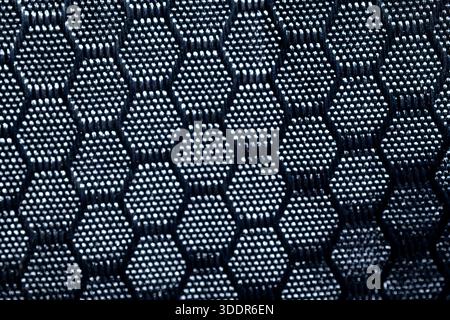 Close up of dark blue synthetic fabric with a hexagonal mesh pattern. Abstract industrial textile background for tech and sports design. Stock Photo