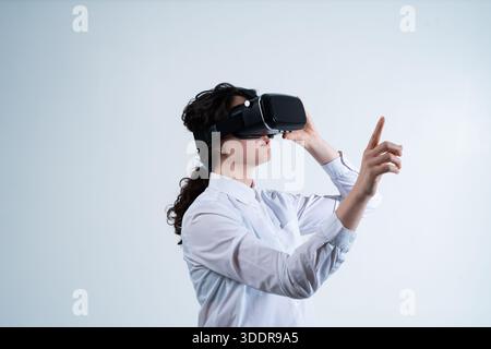 Woman using virtual reality headset and interacting with advanced digital technology through hand gestures in modern futuristic environment Stock Photo