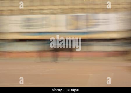 Abstract urban street motion blur. Beige city building and road texture background representing rush hour. Stock Photo