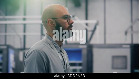 Close Up of Bearded Male IT Engineer In Bright, Modern Data Center. IT Specialist With Glasses Inspects Equipment in Server Room. Concept of Concentra Stock Photo