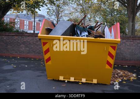 Full UK Skip Bin Rubbish uk waste management logistics garbage trash overflowing awaiting moving to landfill from domestic property after clearout Stock Photo
