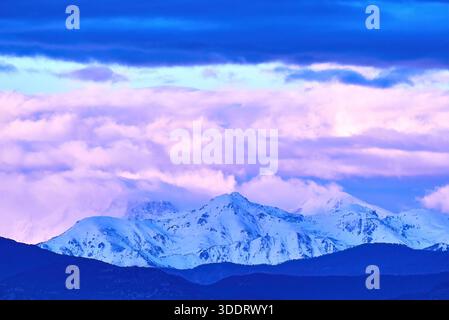 Majestic Snowy Mountain Range Under Blue, Purple and Pink Sky With a Flying Bird Stock Photo