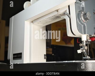 Adjusting a Vintage Sewing Machine Close-Up; Close-up shot of a person's hand setting up or repairing an older, classic sewing machine. Focus on the m Stock Photo