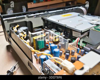 Hands Testing Electronic Circuit Board with Multimeter; Close-up of technician's hands using a multimeter to diagnose or repair complex electronic cir Stock Photo