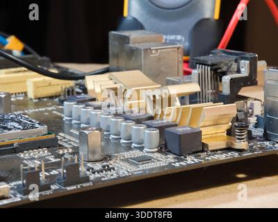Close-up of Computer Motherboard Components; Macro shot showcasing dusty electronic components, gold heatsinks, and capacitors on a dark PC motherboar Stock Photo