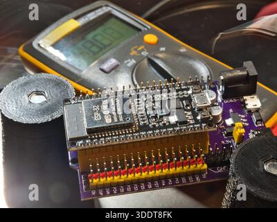 Engineer testing microcontroller board.; Close-up of an engineer testing voltage on a modern microcontroller development board (PCB) using a digital m Stock Photo
