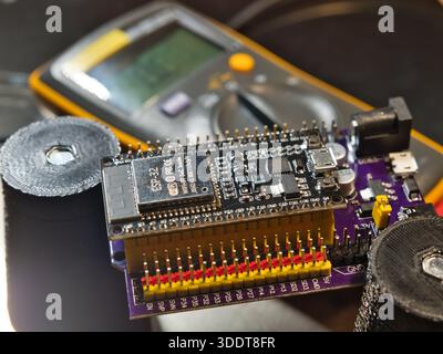 Engineer testing microcontroller board.; Close-up of an engineer testing voltage on a modern microcontroller development board (PCB) using a digital m Stock Photo