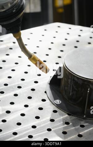 Industrial robot arm with MIG MAG welding torch positioned over perforated fixturing table for gas shielded arc welding of metal parts Stock Photo