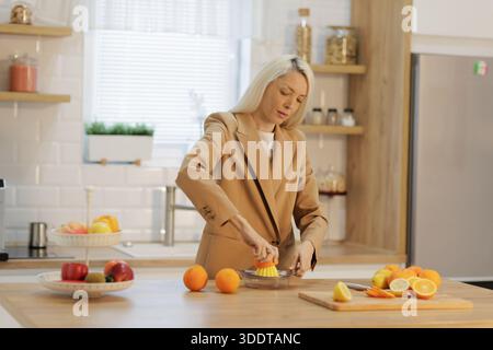 Woman squeezing fresh orange juice in a modern bright kitchen Stock Photo