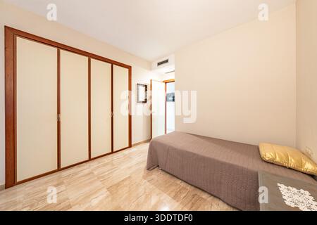 Bedroom Interior with Large Wooden Wardrobe and Single Bed in holiday home Stock Photo
