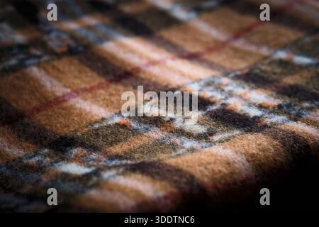 Macro close-up of brown plaid fabric showing woven texture and intersecting lines. Textile pattern, softness, and material detail Stock Photo