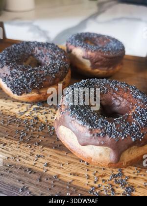 Three donuts with black and white sprinkles on top. One of the donuts has chocolate icing. Selective sharpening Stock Photo