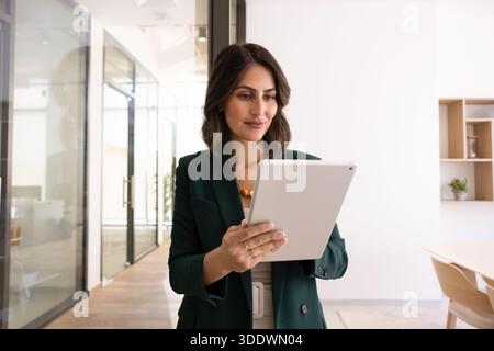 Positive young Latin businesswoman using financial application on digital tablet Stock Photo