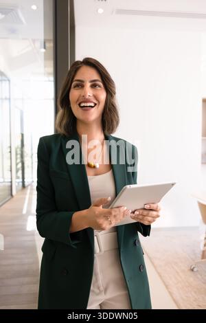 Happy young Hispanic executive woman holding digital tablet computer Stock Photo