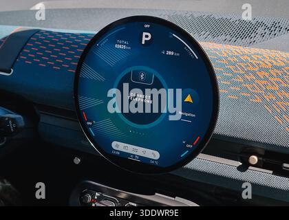 Infotainment system in modern car - close-up shot. Round multimedia screen with main info on driving, temperature, connections and navigation. Stock Photo