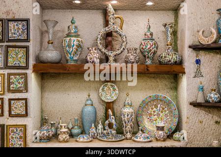 Colourful ceramic vases and plates stand in stone wall niches at Chez Galip Pottery (Çeç Pottery) in Avanos, Turkey. Floral patterns and calligraphy decorate the hand-painted pieces. Since 1979, the workshop has also run the adjoining Hair Museum, where locks from more than 13,000 women hang. Stock Photo