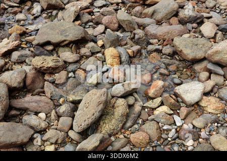 Rocks and stones with puddles of water at a beach abstract textured background Stock Photo
