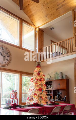 Bright living room interior with a decorated Christmas tree, wooden ceiling and large windows. Warm festive atmosphere with holiday lights creating a Stock Photo