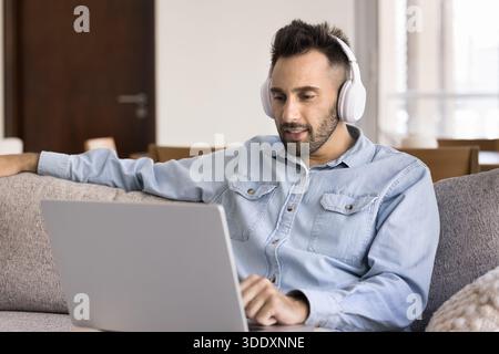 Hispanic man in headphones watching online content on laptop Stock Photo