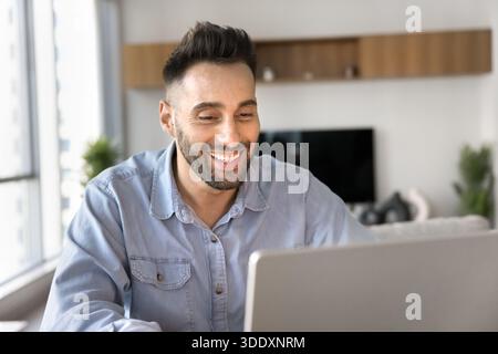 Smiling man engaged in online meeting or webinar using laptop Stock Photo