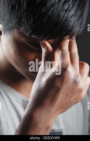 Young man shows signs of stress in a dark room Stock Photo
