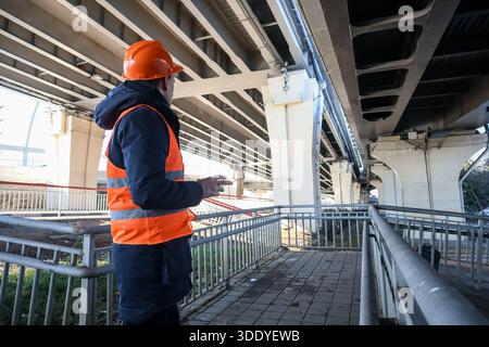 Side view of construction worker in hard hat pointing at concrete overpass elements. Stock Photo