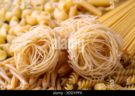 Composition with different tasty uncooked pasta - Italian pasta wallpaper, different types and shapes of pasta layout Stock Photo