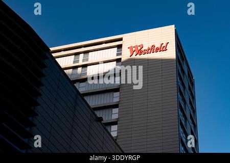 Looking up at Westfield shopping centre sign on the Premier Inn Hotel, Stratford London. The sun casts a shadow on the building with the sign in light Stock Photo
