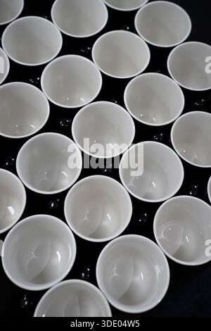 White cups are arranged on a black surface Stock Photo