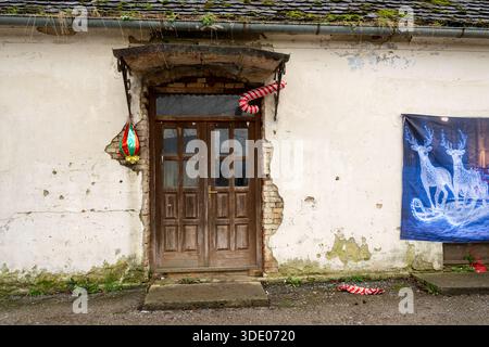 Festive decorations adorn an old building. Someone is celebrating the holidays by hanging candy canes and a reindeer banner on the exterior. Stock Photo