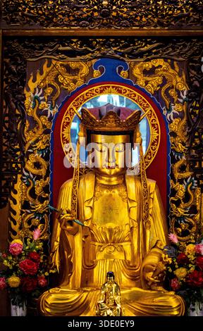 Golden Buddha statue with intricate carvings and floral decorations. Stock Photo