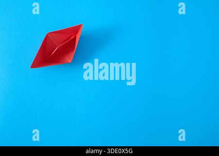 Red paper ship on blue background, top view Stock Photo