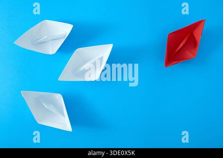 Red and white paper ships on blue background, top view Stock Photo