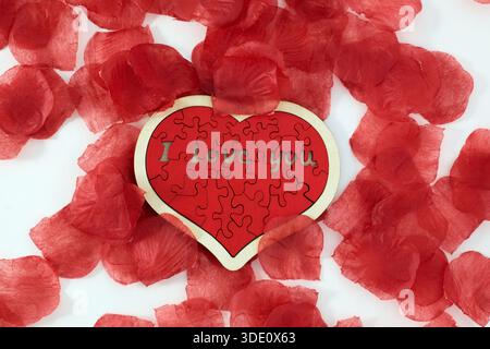 "I love you" wooden puzzle, heart shaped with rose petals Stock Photo