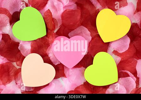 Heart shape sticky notes laying on rose petals Stock Photo