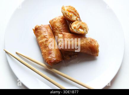 Plate with crispy fried spring rolls (Chinese rolls) served with chopsticks on a white background. Typical dish of Asian cuisine. Overhead view. Stock Photo