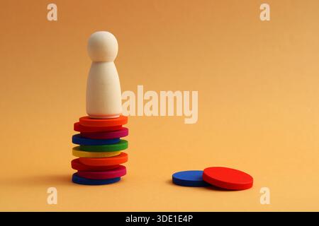 Wooden figure balanced on colored circles that support it Stock Photo