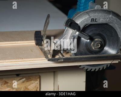 Close-up of Circular Saw Blade Cutting Plywood; Detailed view of a powerful handheld circular saw blade slicing through plywood on a workbench. Essent Stock Photo
