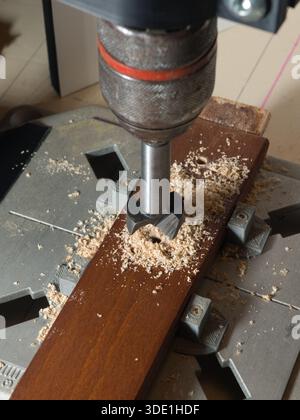 Drill Press Cutting Wood with Forstner Bit; Close-up of a woodworking drill press using a specialized bit (likely Forstner) to bore a clean, flat-bott Stock Photo