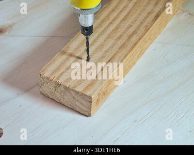 Drilling Wood Plank with Precision Rotary Tool; Close-up shot of a small drill bit from a precision rotary tool boring a hole into a raw piece of lumb Stock Photo