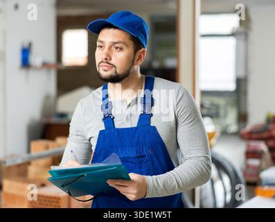Builder making notes on indoor construction site Stock Photo