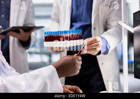 Close up of scientists examining a blood sample vial for testing, biotechnology research for genetics and molecular science. Advanced medicine and innovation in modern laboratory. Stock Photo