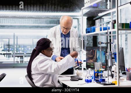 Diverse researchers in lab workspace conducting experiments and analyzing DNA tissue in jars. Biotechnology, genetics and chemistry tools highlight innovation in medicine. Molecular biology. Stock Photo