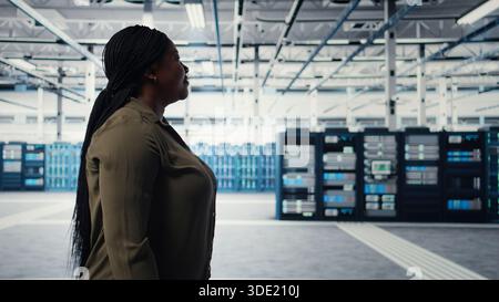 Manager walking in data center, overseeing large scale IT hardware to maintain seamless operations. Server room worker doing network management for increased uptime, camera A Stock Photo