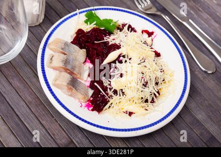 Sliced herring with grated beetroot and cheese served on table Stock Photo