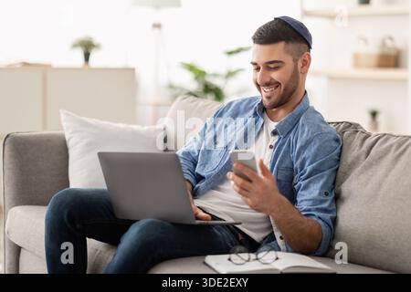 Happy jewish man using mobile phone and laptop Stock Photo