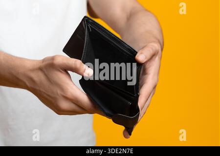 Unrecognizable man showing empty wallet at studio, closeup Stock Photo