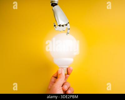 Concept of AI innovation and human-robot collaboration, showing a human and robotic hand touching a glowing white light bulb. Symbol of future technol Stock Photo