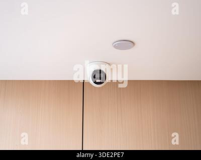 Modern indoor white dome CCTV camera mounted on ceiling for surveillance and building security, representing safety technology, smart monitoring, and Stock Photo